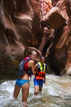 Young couple under big rock at the canyon of Wadi Mujib