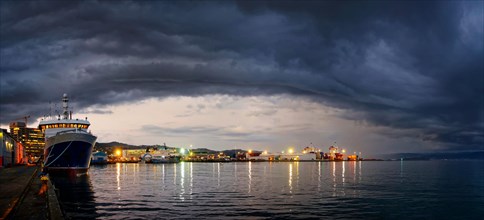 Harbour and Queens Wharf illuminated at sunset with dark storm clouds