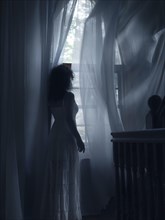Woman in a white dress standing by a window with flying curtains in a dark room