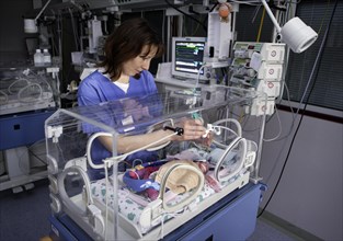 Nurse at incubator with newborn baby
