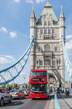 Red double-decker bus crosses Tower Bridge