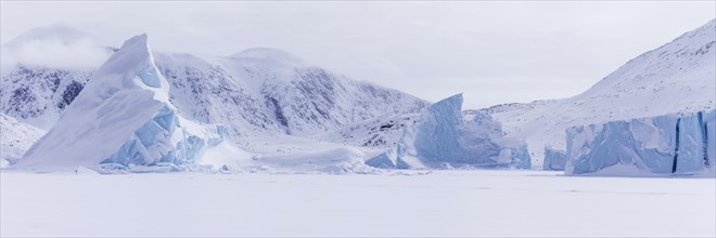 Panoramic view of snow-covered mountains seen from a frozen fjord