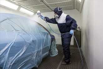 Vehicle painter during a partial painting of a car in the spray booth