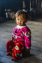 Little girl sits on stool in hut