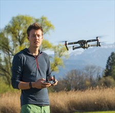 Young man controlling flying quadrocopter