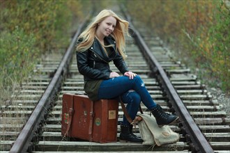 Young woman sitting on a suitcase