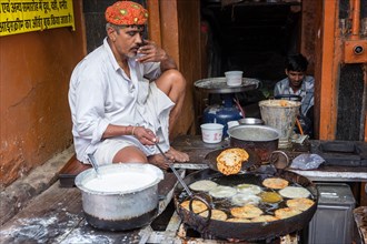 A man is preparing savoury fried snacks at a street kitchen