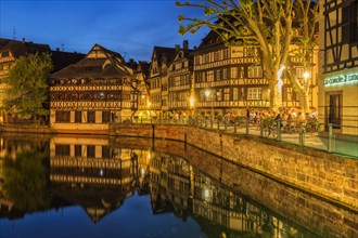 People on a restaurant terrace along the ILL canal at twilight