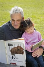 Father reading book to daughter