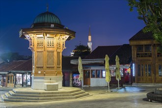 Illuminated Sebilj ottoman-style wooden fountain at sunrise