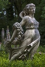Female sculpture with a band of flowers behind acanthus
