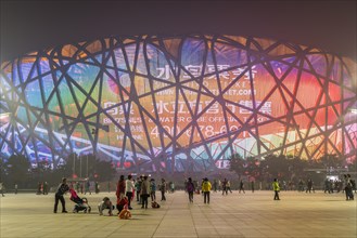 People on square in front of illuminated National Stadium in the Olympic Park