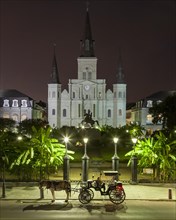 Jackson Square and St. Louis Cathedral at night with horse and carriage waiting for passengers