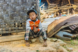 Little boy sitting in front of log cabin