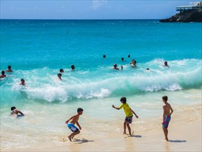 Tourists bathing in high waves at Maho Beach