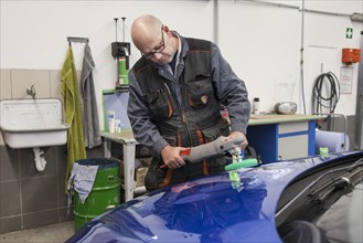 Coachbuilder master with the polishing machine on the car