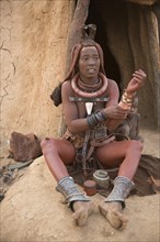 Himba woman with child in front of the hut