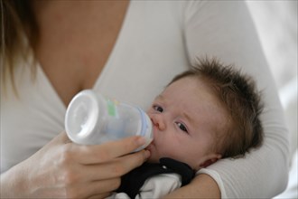 Mother feeds baby with baby bottle