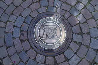Manhole cover with the symbol for the formula Mons