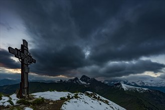 Cross on the summit of Zafernhorn with dark clouds