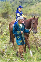 Kazakh man walking around with his son on a horse after Circumcision Sundet Toi ceremony