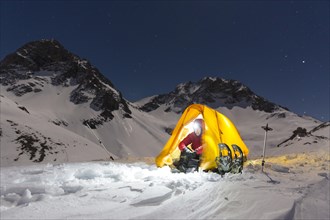 Snowshoe hikers in an illuminated tent in the snow on the Madelejoch