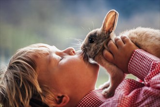 Four-year-old girl kissing rabbit