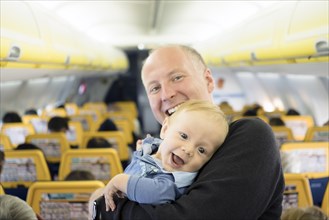 Father laughing with his six months old baby boy in the airplane