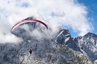 Paraglider against cloudy peak of the Alpspitze