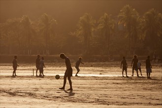 Young people playing football on the beach