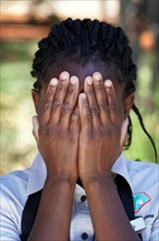 Namibian woman of the Ovambo tribe holding hands in front of her face