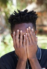 Namibian man of the Ovambo tribe holding hands in front of his face