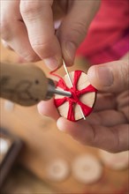 Button maker in third step of Posamentenknopfe production holding wooden blank with vise and carefully stitching and wrapping red yarn into star pattern