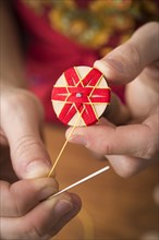 Button maker stitching and wrapping red and yellow yarn into star pattern