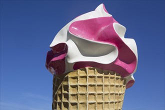 Large ice sculpture made of plastic as advertisement for an ice cream parlour in front of a blue sky