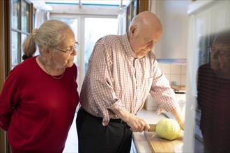 Senior couple cutting vegetables in the kitchen