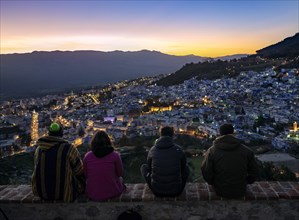 People sitting on a wall overlooking city Chefchauoen