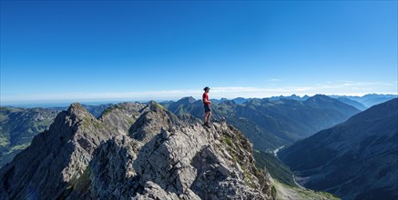 Hiker stands on rocks looking into the distance