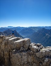 Hiker reaches arms into the air