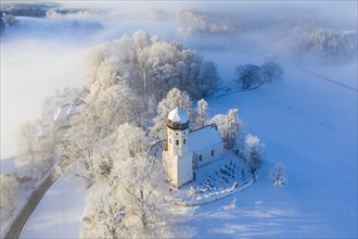 Snow-covered church St. Johann Baptist. Fog mood