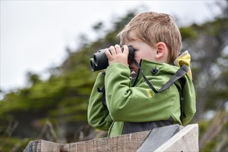 Interested boy looking through binoculars