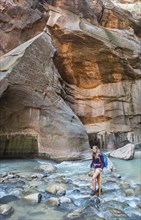 Hiker walking through river