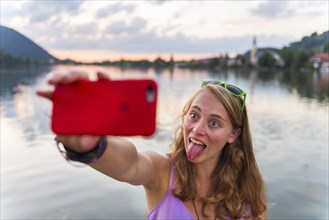 Young woman taking selfie with outstretched tongue