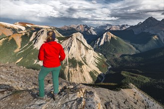 Female hiker looks from summit over mountain landscape