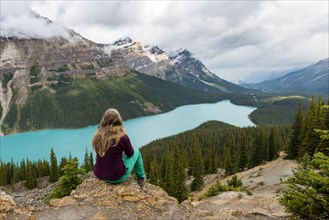 Young woman sitting on a stone looking into nature
