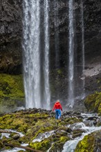 Hiker in front of a high waterfall