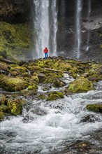 Hiker in front of a high waterfall