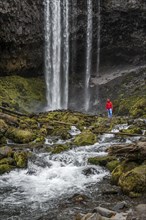 Hiker in front of a high waterfall