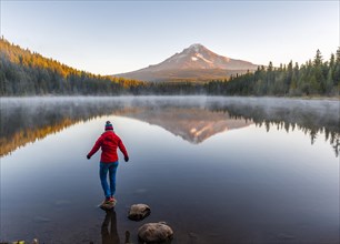 Young woman looking at view of volcano Mt. Hood with reflection in lake Trillium Lake