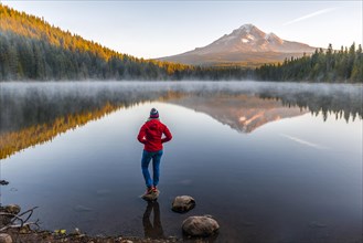 Young woman looking at view of volcano Mt. Hood with reflection in lake Trillium Lake